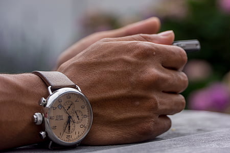person wearing silver-colored chronograph watch leaning on gray surface thumbnail