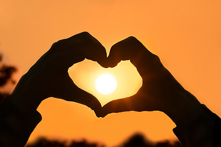 Person making a heart shape with hands at sunset thumbnail