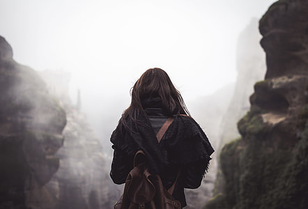 woman carrying brown leather backpack standing near rock formation thumbnail