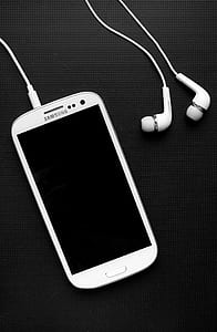 white Samsung Galaxy smartphone beside earphones thumbnail