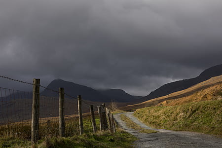 dirtroad beside fence with barbed wire under cloudy sky at daytime thumbnail