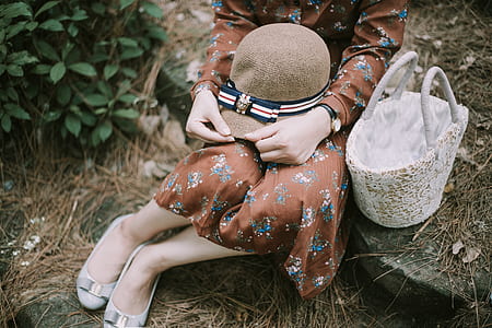 woman wearing brown floral dress with hat on lap sitting on stairs with basket on her side thumbnail