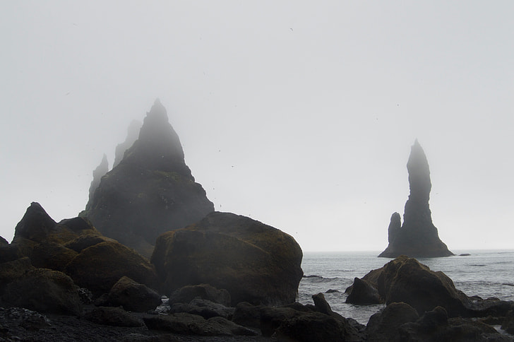 black rock formation near body of water
