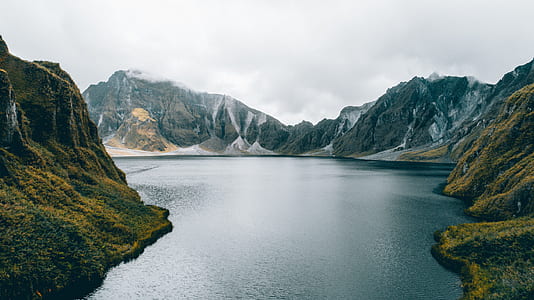 body of water surrounded by mountains during daytime thumbnail