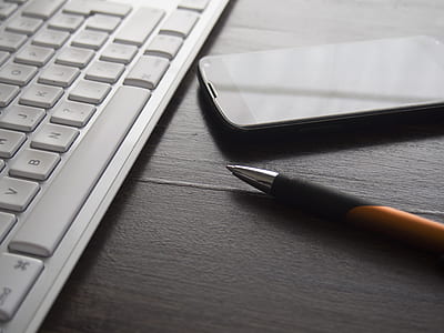 black Android smartphone beside white keyboard and ballpoint pen thumbnail