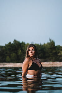 woman in black bikini in body of water looking sideways thumbnail