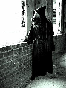 grayscale photography of person wearing robe with hood and gas mask thumbnail