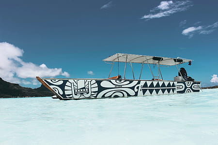Person Sitting on White and Blue Boat Under Blue Sky thumbnail