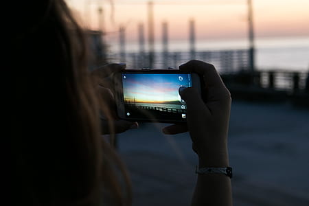 Brown Haired Woman Taking a Photo of Sunset thumbnail