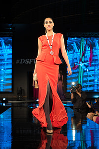 woman in red sleeveless dress with black stockings walking on black platform thumbnail