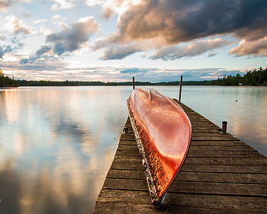 brown wooden canoe on dock near lake thumbnail