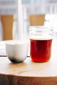 white ceramic mug beside clear glass container filled with brown substance on brown table thumbnail