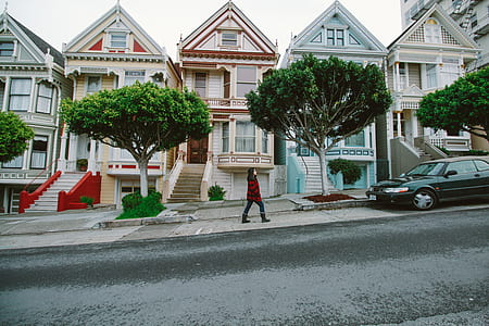 Woman Walking Toward Black Sedan Parked In Front of Colorful Houses thumbnail