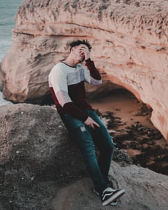 man sitting on cliff during daytime thumbnail
