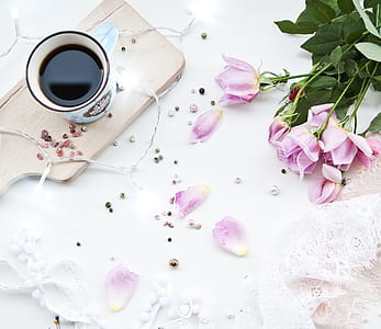 cup filled with coffee beside pink rose flowers thumbnail