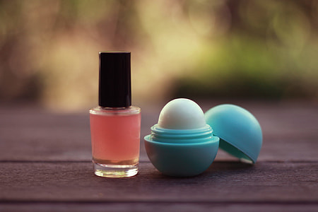 selective focus of a nail polish bottle and lip balm on wooden surface thumbnail