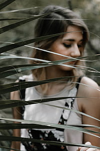 woman looking downward behind leaf thumbnail