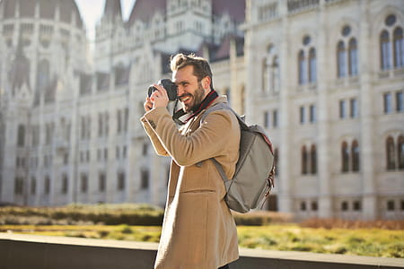 Young bearded adult man in long overcoat using a camera to capture images thumbnail