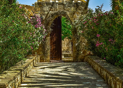brown concrete arch gate surrounded by flowers thumbnail