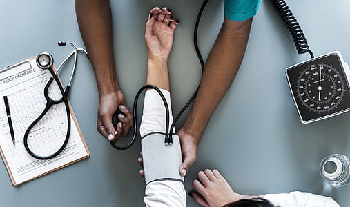 person in teal shirt monitors person on white dress blood pressure using sphygmomanometer thumbnail