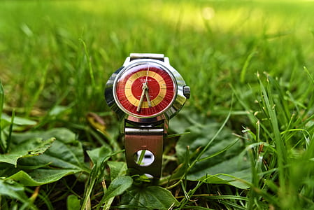 round silver-colored analog watch with brown band displaying at 5:32 on green grass field thumbnail