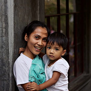 woman leaning on wall carrying boy thumbnail