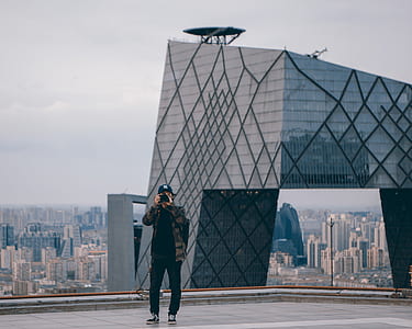 man standing on roof holding black camera thumbnail