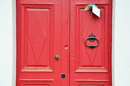 closed red wooden door with mails inserted at top thumbnail