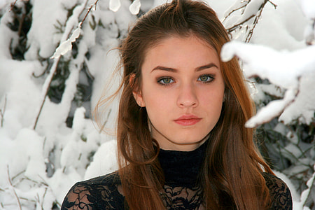 woman wearing black lace mesh turtle neck top surrounded by snow-filled trees thumbnail