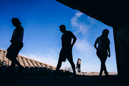 silhouette of three persons standing on roof thumbnail