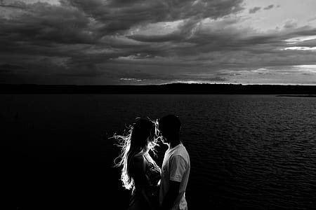 grayscale photo of man and woman kissing beside the body of water thumbnail