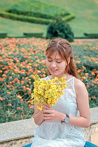 Woman Wearing White Top Holding Yellow Petaled Flowers thumbnail