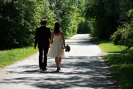 bride and groom walking on gray pathway during daytime thumbnail