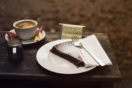 slice of cake on round white plate beside cup on saucer thumbnail