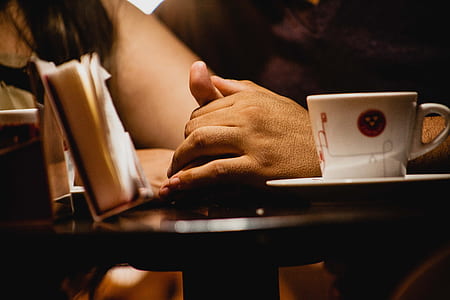 person's hand on top of table near white mug thumbnail