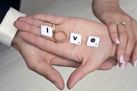 two person's hand holding gold-colored ring thumbnail