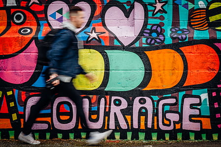 time lapse of man walking near wall art during daytime thumbnail