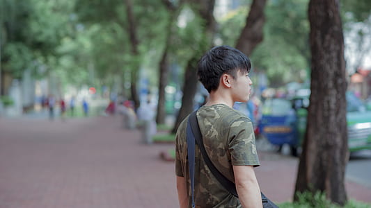 Man in Green and Grey Camouflage Shirt While Standing Behind Tree thumbnail