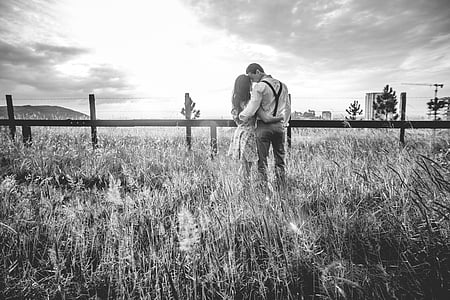gray scale photography of man and woman standing near fencev thumbnail