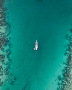 white boat on calm body of water in aerial view thumbnail