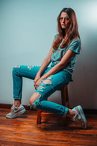 woman in teal shirt and jeans seating on brown wooden chair thumbnail