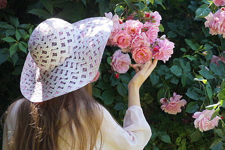 woman with summer hat holding a pink petaled flower thumbnail