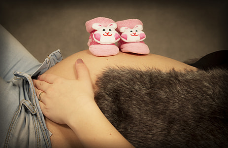 toddler's pair of pink bootees on human belly thumbnail