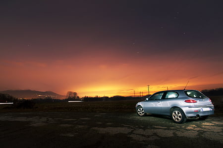 silver 3-door hatchback on dirt road at golden hour thumbnail