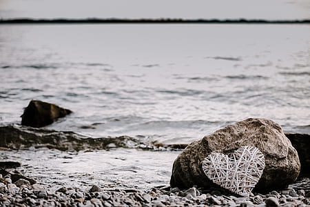 string heart on stone near body of water thumbnail