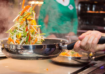 person holding grey stainless steel frying pan with cooked vegetable thumbnail