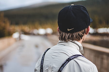selective focus photography of person wearing black Nike cap facing mountains thumbnail