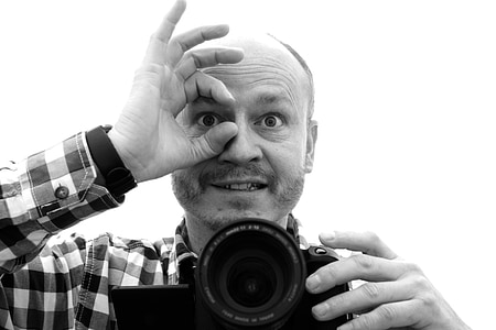 grayscale photo of man holding black DSLR camera thumbnail