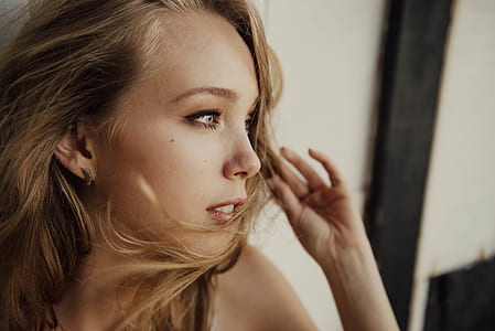 wide-aperture photography of woman leaning on beige wall posing for photo during daytime thumbnail