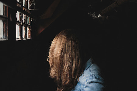 person wearing blue denim jacket standing near window thumbnail